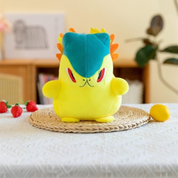 Adorable Quilava Pokemon plush toy in yellow with teal head and orange flame accents, sitting on a woven mat on a table.